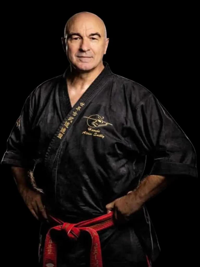 Hanshi Alain Sailly en gi noir, ceinture rouge, fond noir