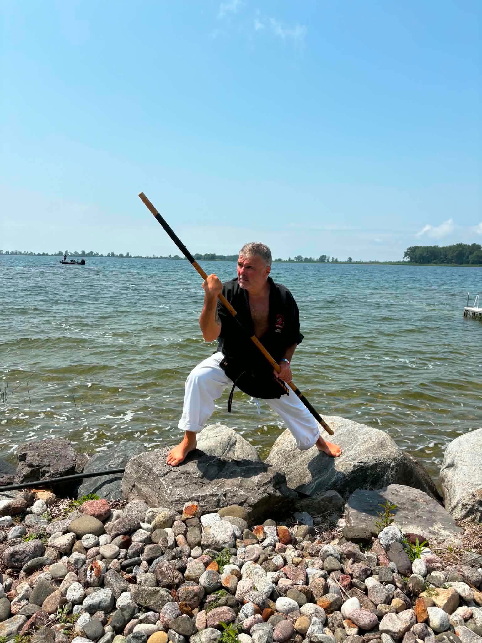 Kyoshi Denis Paquet en posture au bo sur les rochers